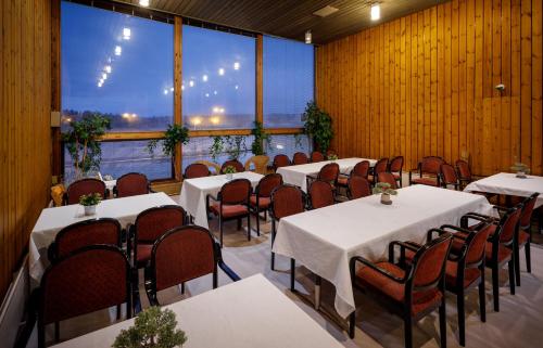 um restaurante com mesas e cadeiras e uma grande janela em Hotelli Leikari em Kotka