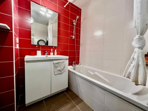 La salle de bains est pourvue d'un lavabo blanc, d'une baignoire et de carreaux rouges. dans l'établissement Superbe appartement cosy, à Annecy