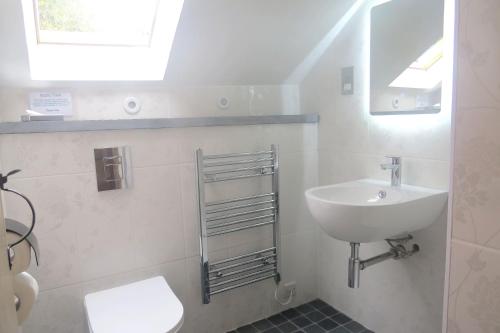 a white bathroom with a sink and a toilet at Galleri hot tub 2 bed ensuite in Blaencelyn