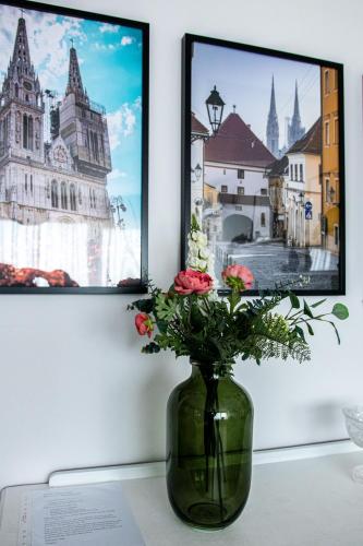 a green vase with flowers in front of a painting at Apartment Gallery Zagreb in Zagreb