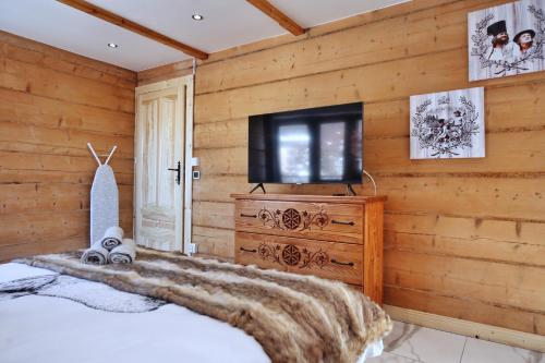 - une chambre avec un lit et une télévision sur un mur en bois dans l'établissement WILLA SZELIGÓWKA KOŚCIELISKO, à Kościelisko