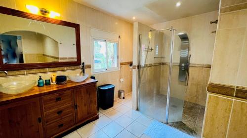 a bathroom with a shower and two sinks and a mirror at Villa La Caze Plain'itude Saint Paul in Saint-Paul