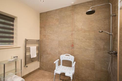 a shower with a white chair in a bathroom at Vesta View in Hexham