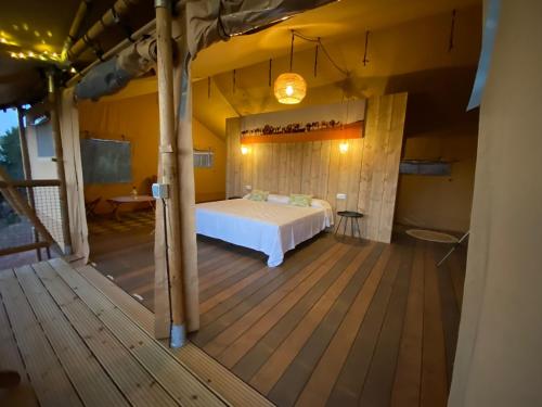 1 dormitorio con 1 cama en una terraza de madera en Glamping VALL de CODÓ en Terrades