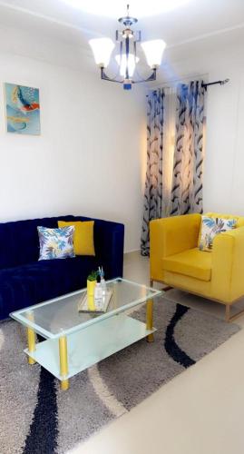 uma sala de estar com um sofá, uma mesa e uma cadeira amarela em Kolyséhome -Studio, bonamoussadi carrefour eto’o em Douala