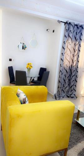um sofá amarelo num quarto com uma mesa e cadeiras em Kolyséhome -Studio, bonamoussadi carrefour eto’o em Douala