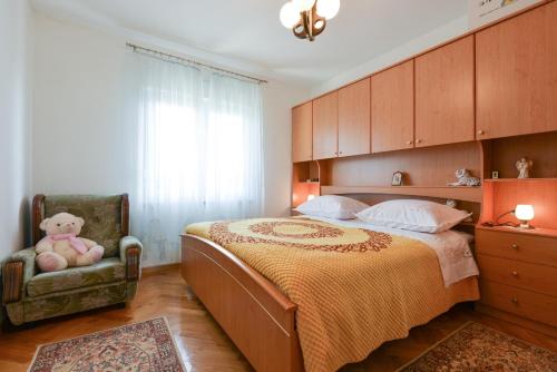 a bedroom with a bed and a chair with a teddy bear at Apartmani Blažo in Kali