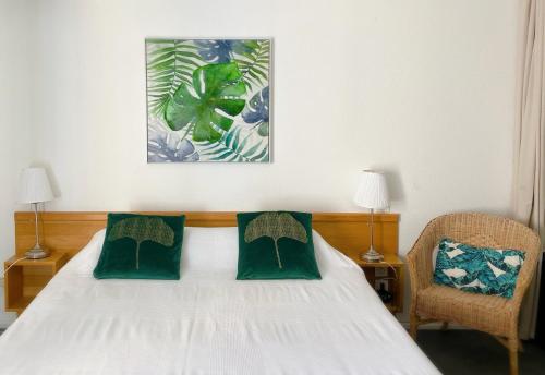 sypialnia z białym łóżkiem z 2 zielonymi poduszkami w obiekcie Le Clos Nicolas w mieście Eugénie-les-Bains