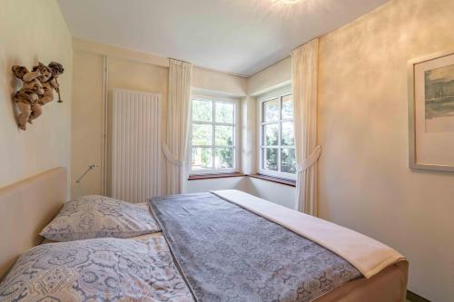 a bedroom with a bed and two windows at Ferienwohnung Dünenblick in Sankt Peter-Ording