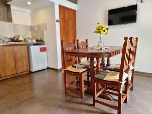 una cocina con mesa y sillas con un jarrón de flores. en Monoambiente temporal Jujuy en San Salvador de Jujuy