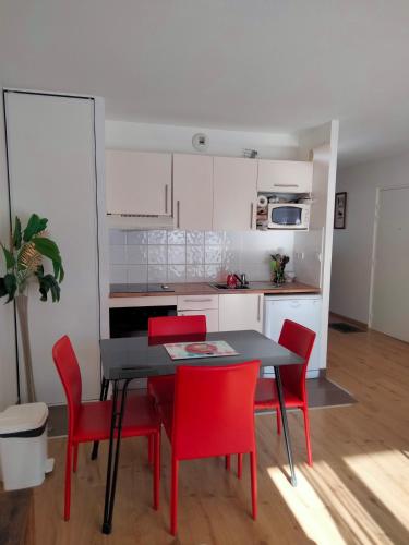 a kitchen with a black table and red chairs at charmant T2 formiguères les esplaneilles in Formiguères