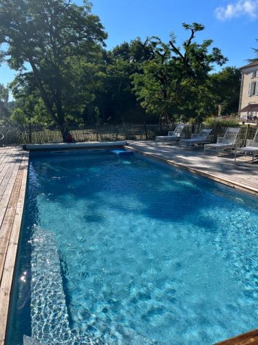 a swimming pool with blue water in a yard at Lou Castet de Lussolle - Chambres d'hôtes in Losse