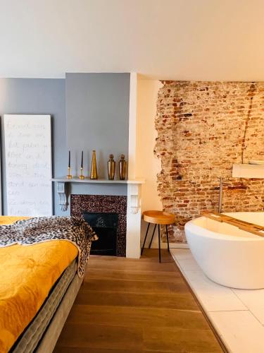 a bedroom with a bed and a bath tub and a fireplace at Georgia's Bathhouse in Breda