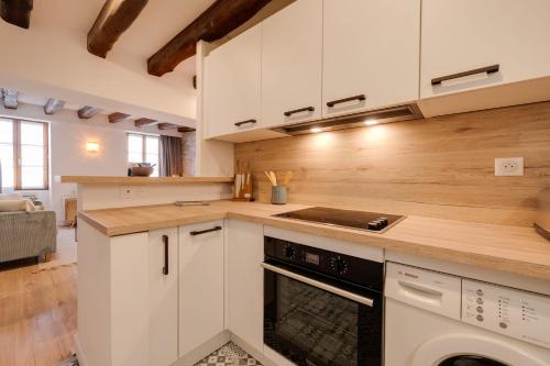 une cuisine avec des armoires blanches et un four à plaques de cuisson dans l'établissement Le Grenette - Appartement pour 2 à 4 personnes en plein coeur d'Annecy, à Annecy