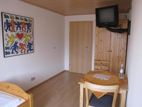 a room with a table and a television and a bedroom at Hotel Restaurant Parthenon in Otterbach