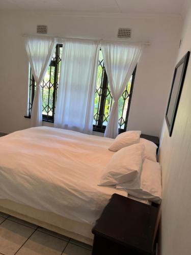 1 dormitorio con 1 cama con sábanas blancas y ventana en Mtunzi Park, 39 Peaceful shores, en Scottburgh