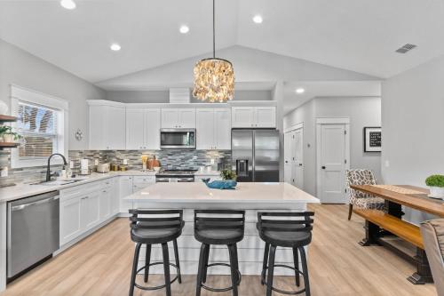 a kitchen with white cabinets and a island with bar stools at Brand New Entire Home close to beach in St. Augustine