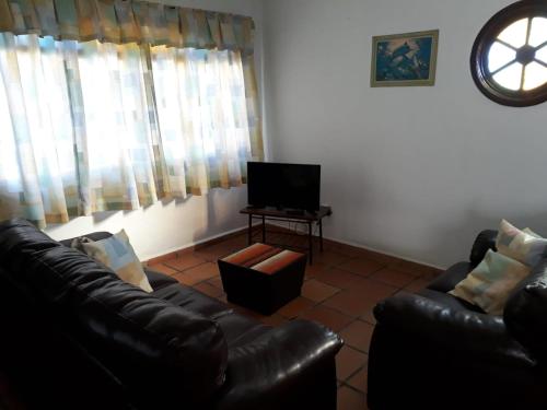 ein Wohnzimmer mit 2 Ledersofas und einem TV in der Unterkunft Casa no Guaraú - Peruíbe in Peruíbe