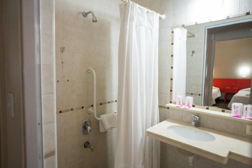 uma casa de banho com um chuveiro, um lavatório e um espelho. em Hotel Posada Del Sol em Salta