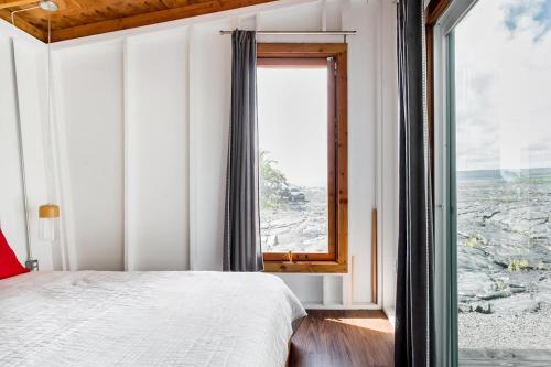 a bedroom with a bed and a large window at THE OHANA HOUSE, Amazing Tiny Home on A Volcanic Lava Field! in Kehena