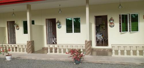 Una casa blanca con un porche con flores. en Margereth Cottage, en Kuala Penyu