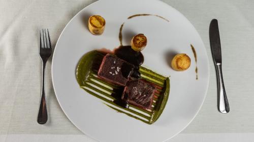 a plate of food on a table with fork and knife at Das-Schmidt Privathotel in Mörbisch am See