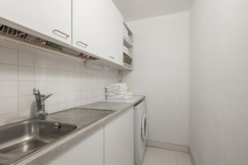 una pequeña cocina con fregadero y armarios blancos en Comfortable city home, en Helsinki