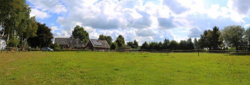 a large field with a barn and a fence at Gastenhuis de Veenstraal Gieterveen in Gieterveen