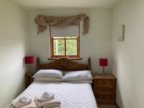 a bedroom with a bed with two lamps and a window at Two Bedroom Glen View Free Parking in Inverness