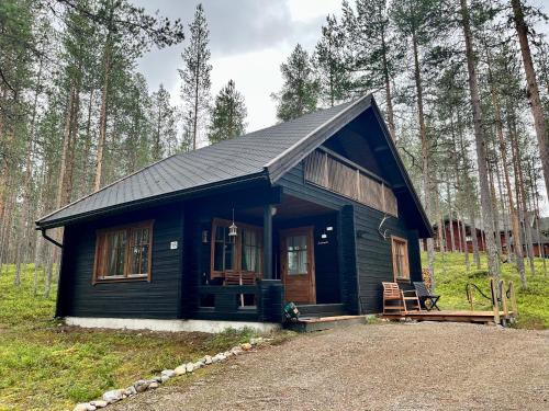 una piccola cabina nera in mezzo a una foresta di Pyhä Saukonpiilo a Pelkosenniemi