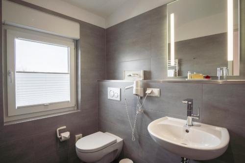 a bathroom with a white toilet and a sink at Hotel Elysee in Seligenstadt