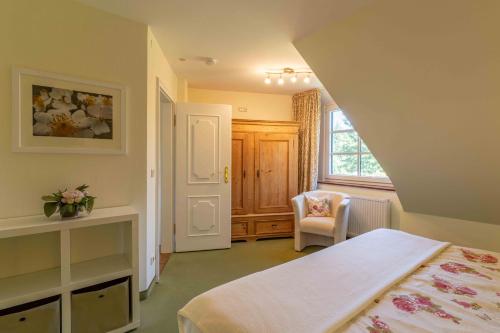 a bedroom with a bed and a chair and a window at Feriewohnung Kaminstuv in Sankt Peter-Ording