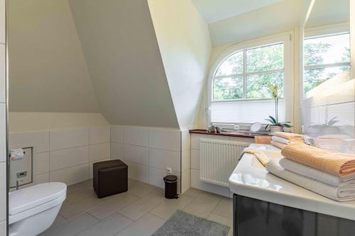 a bathroom with a sink and a toilet and a window at Feriewohnung Kaminstuv in Sankt Peter-Ording