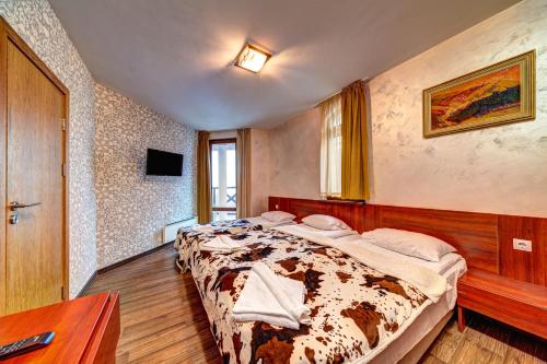 een slaapkamer met een bed en een televisie. bij Вили Forest Nook in Pamporovo