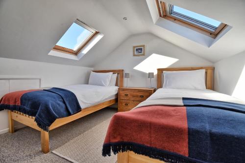 two beds in a attic bedroom with two windows at Spindrift - views of Chesil beach dog friendly in Weymouth