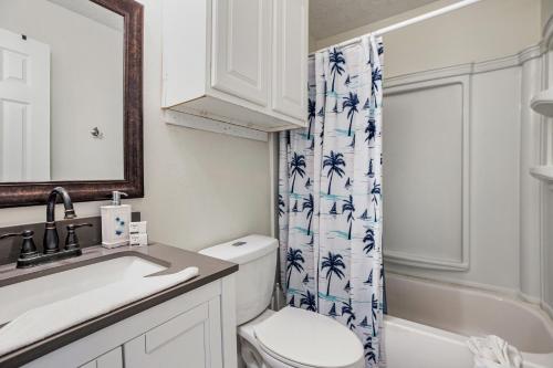 uma casa de banho com um WC, um lavatório e uma cortina de chuveiro em Bungalow by the Bay em Galveston