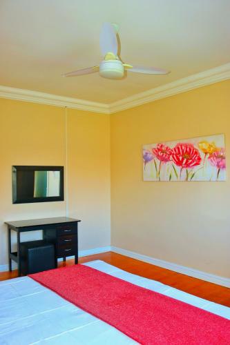 a bedroom with a ceiling fan and a red rug at Seas of Ships Guest House in Durban
