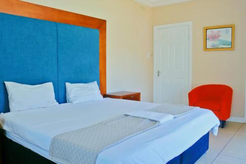 ein Schlafzimmer mit einem großen Bett und einem roten Stuhl in der Unterkunft Seas of Ships Guest House in Durban