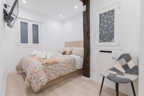 a white bedroom with a bed and a chair at Beautiful Old Town by Next Stop Bilbao in Bilbao