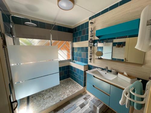y baño con azulejos azules, lavabo y ducha. en La Villa Soalic, en Cilaos