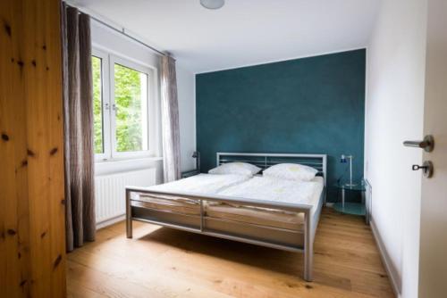 een slaapkamer met een bed met een blauwe muur bij GASTHAUS Porzelt-Ferien im Weingut-Wohnung 3 in Klingenmünster