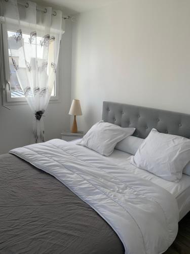 une chambre avec un grand lit blanc avec une fenêtre dans l'établissement Agréable appartement à 200 m de la plage - NAEL, à Ploemeur