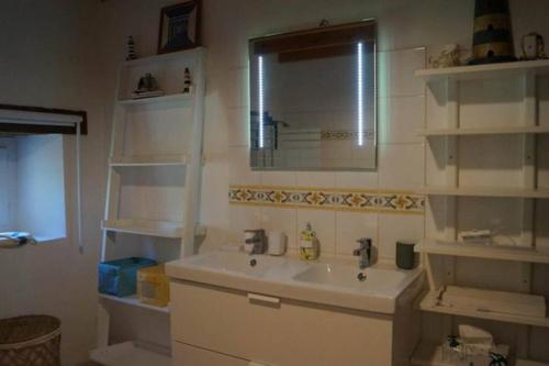baño con lavabo, espejo y estanterías en Gîte rural, en Saint-Pierre-sur-Dropt