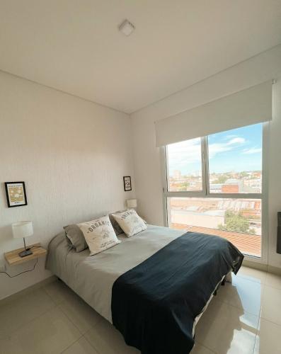 um quarto com uma cama grande e uma janela grande em Hermoso departamento nuevo en Bahía Blanca piso 4 em Bahía Blanca
