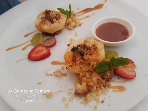a white plate with some food and a sauce at Das-Schmidt Privathotel in Mörbisch am See