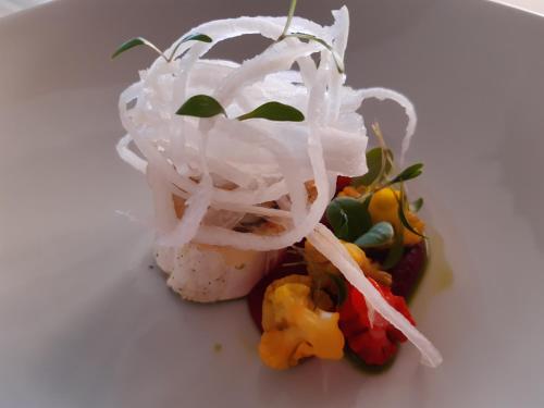 a dish with onions and vegetables on a white plate at Das-Schmidt Privathotel in Mörbisch am See