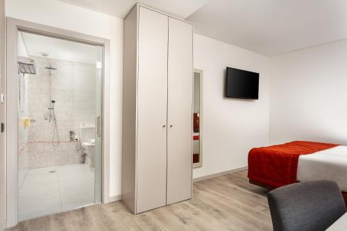 a bedroom with a bed and a bathroom with a shower at Empire Marquês Hotel in Lisbon