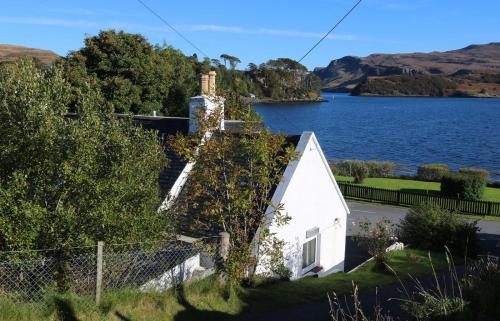 a white house with ivy on the side of a lake at Tarradale Cottage in Portree