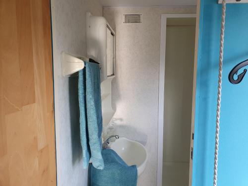 La salle de bains est pourvue d'un lavabo et de serviettes bleues sur le mur. dans l'établissement CS 61 - Vakantiepark Callassande, à Callantsoog