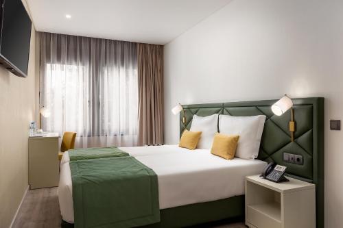 a hotel room with a large bed with yellow pillows at Empire Marquês Hotel in Lisbon